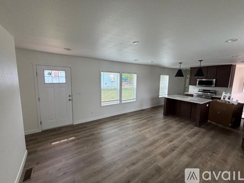 A spacious room with wooden flooring and a kitchen area with brown cabinets.