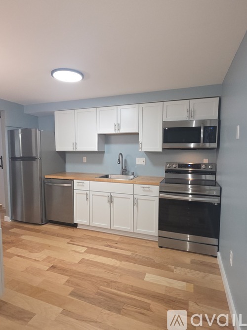 A kitchen with white cabinets and wooden flooring.