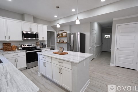 A kitchen with white cabinets and a marble countertop.
