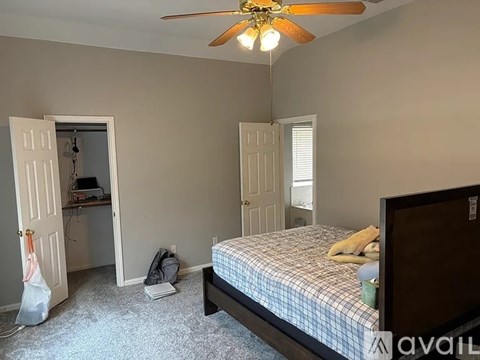 A bedroom with a bed, a ceiling fan, and a window with blinds.