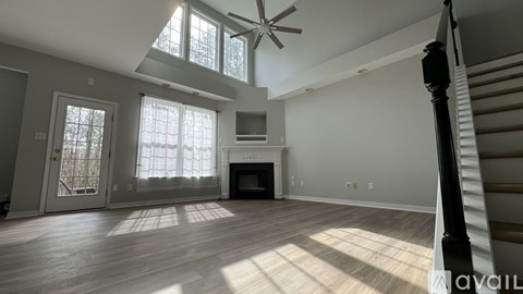 A spacious living room with a fireplace and a staircase on the right side.