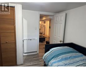 A bedroom with a bed, a radiator, and a door leading to another room.