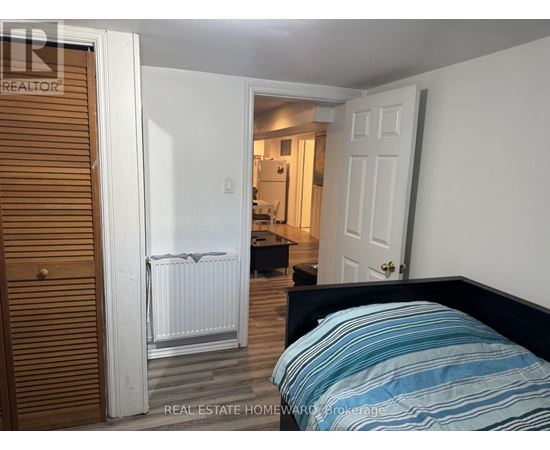 A bedroom with a bed, a radiator, and a door leading to another room.