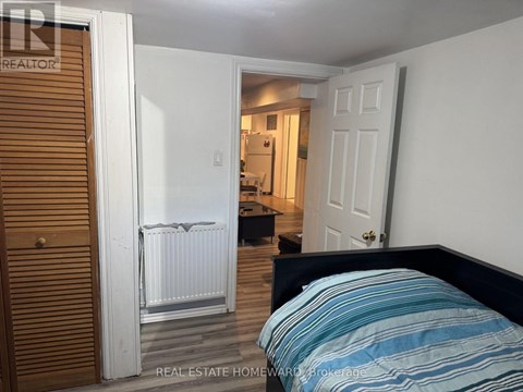 A bedroom with a bed, a radiator, and a door leading to another room.