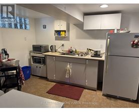 A kitchen with a refrigerator, microwave, and oven.