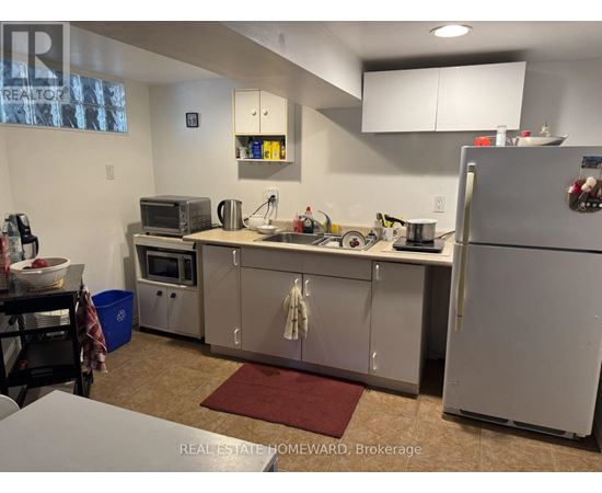 A kitchen with a refrigerator, microwave, and oven.
