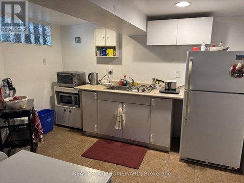 A kitchen with a refrigerator, microwave, and oven.