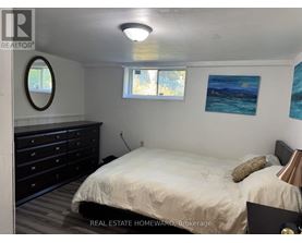 A bedroom with a bed, dresser, and two windows.