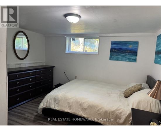 A bedroom with a bed, dresser, and two windows.