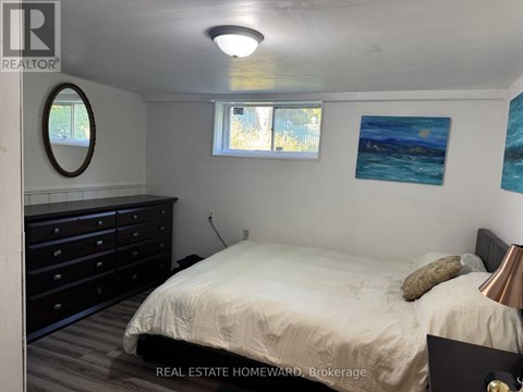 A bedroom with a bed, dresser, and two windows.
