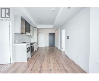 A spacious kitchen with white cabinets and a wooden floor.