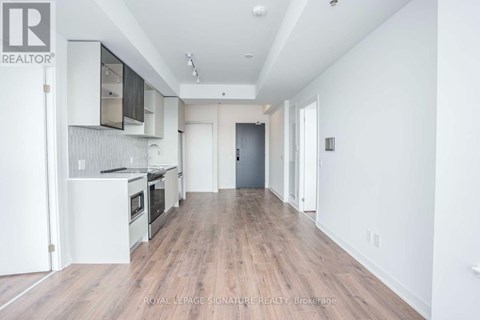 A spacious kitchen with white cabinets and a wooden floor.