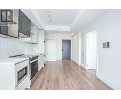 A spacious kitchen with white appliances and wooden floors.