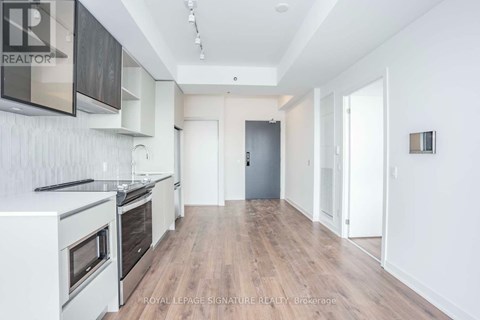 A spacious kitchen with white appliances and wooden floors.
