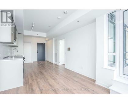 A spacious room with wooden flooring and white walls.