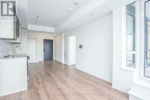 A spacious room with wooden flooring and white walls.