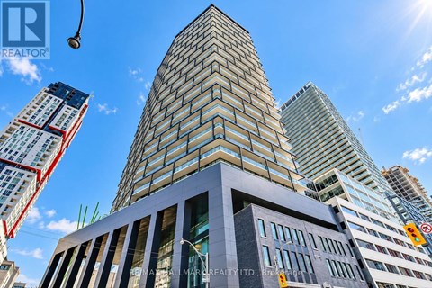 A tall building with a glass facade stands in front of other skyscrapers.