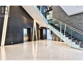 A spacious hallway with a glass staircase and a black wall.