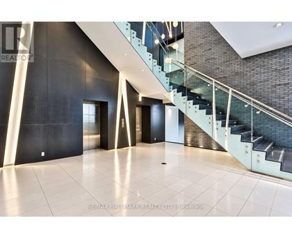 A spacious hallway with a glass staircase and a black wall.