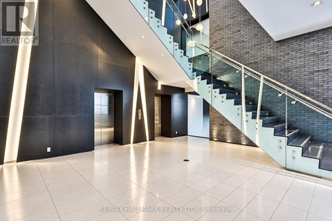 A spacious hallway with a glass staircase and a black wall.