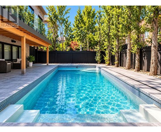 A swimming pool in a backyard with a wooden deck and a black fence.