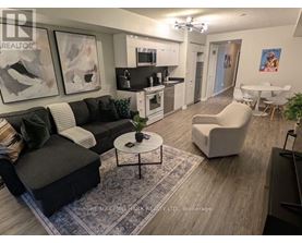 A living room with a black couch, a white chair, and a coffee table.