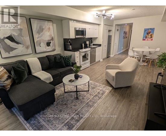 A living room with a black couch, a white chair, and a coffee table.