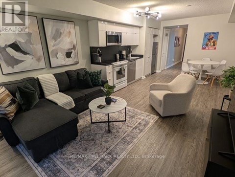 A living room with a black couch, a white chair, and a coffee table.