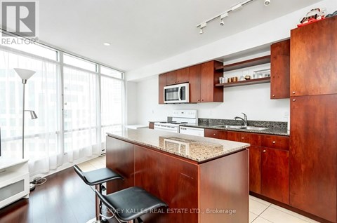 A kitchen with dark wood cabinets and a granite countertop.