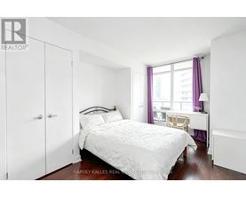 A bedroom with a white bed and a window with purple curtains.