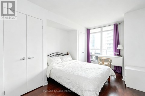 A bedroom with a white bed and a window with purple curtains.