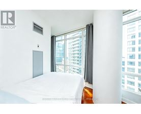 A bedroom with a large bed and a window overlooking a cityscape.