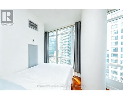 A bedroom with a large bed and a window overlooking a cityscape.