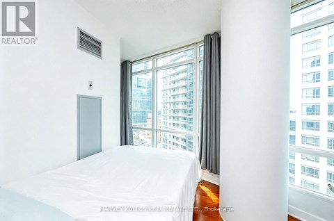 A bedroom with a large bed and a window overlooking a cityscape.