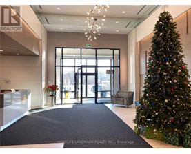 A Christmas tree stands next to a set of double doors in a lobby.