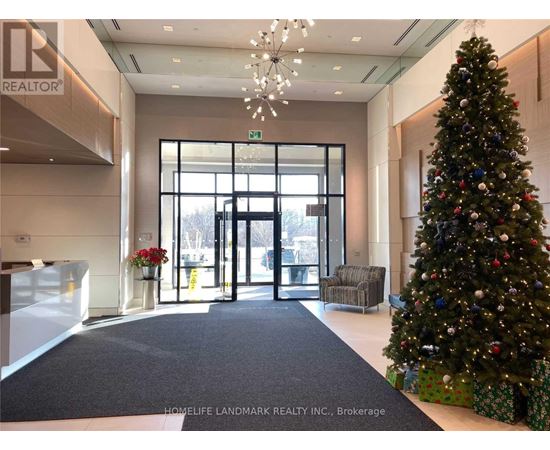 A Christmas tree stands next to a set of double doors in a lobby.