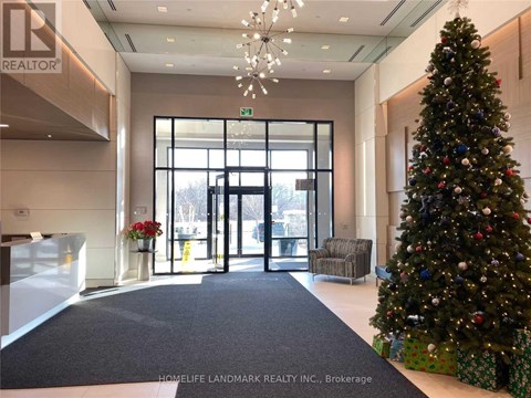 A Christmas tree stands next to a set of double doors in a lobby.