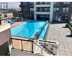 A swimming pool on a rooftop with a glass railing.