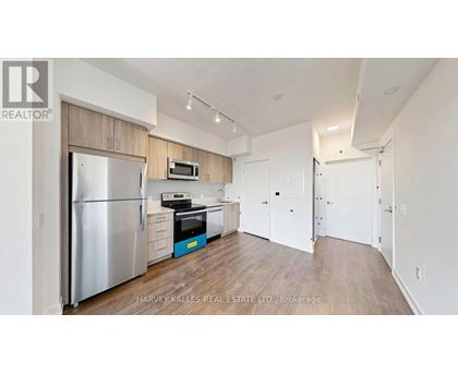 A kitchen with a refrigerator, microwave, and oven.