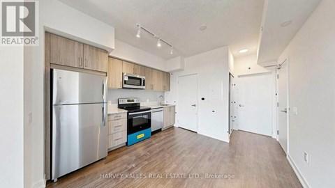 A kitchen with a refrigerator, microwave, and oven.