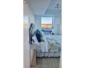 A bedroom with a bed and a window overlooking a balcony.