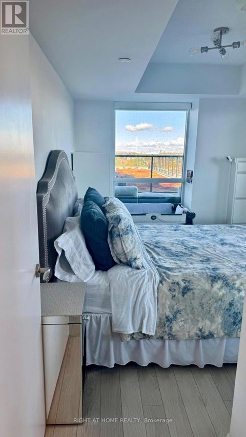 A bedroom with a bed and a window overlooking a balcony.