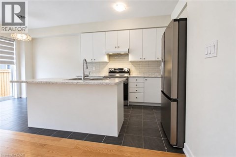 A modern kitchen with white cabinets and a marble countertop.