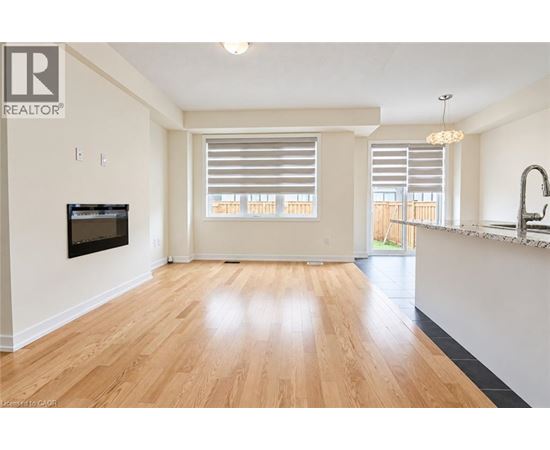 A spacious living room with wooden flooring and a television mounted on the wall.