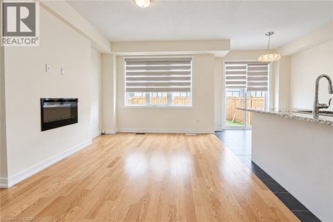 A spacious living room with wooden flooring and a television mounted on the wall.