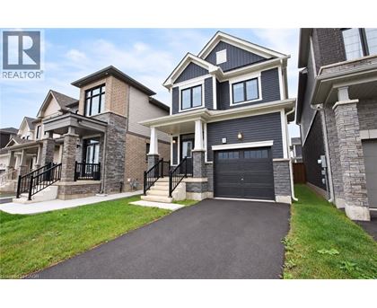 A large, modern house with a black garage door is for sale.