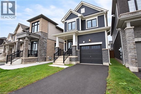 A large, modern house with a black garage door is for sale.