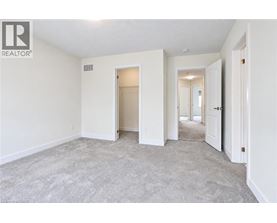 A spacious empty room with a carpeted floor and white walls.