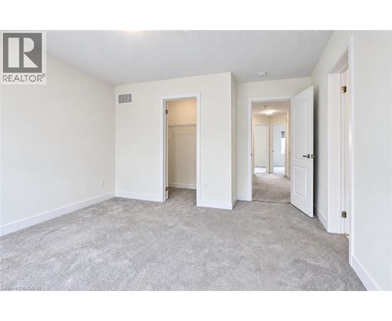 A spacious empty room with a carpeted floor and white walls.