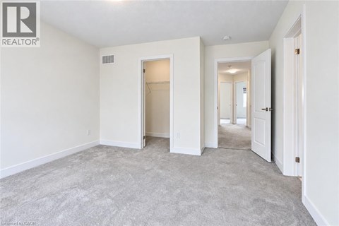 A spacious empty room with a carpeted floor and white walls.